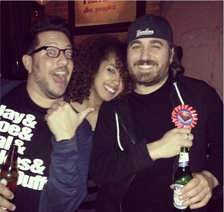 Sal pointing at Q and Emily Amick leaning on Q's shoulders behind him on Q's birthday.